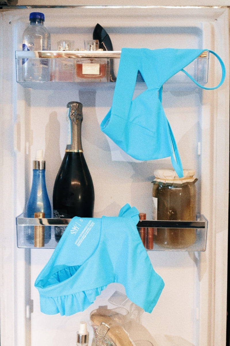 Open refrigerator with blue polewear hanging on the shelves